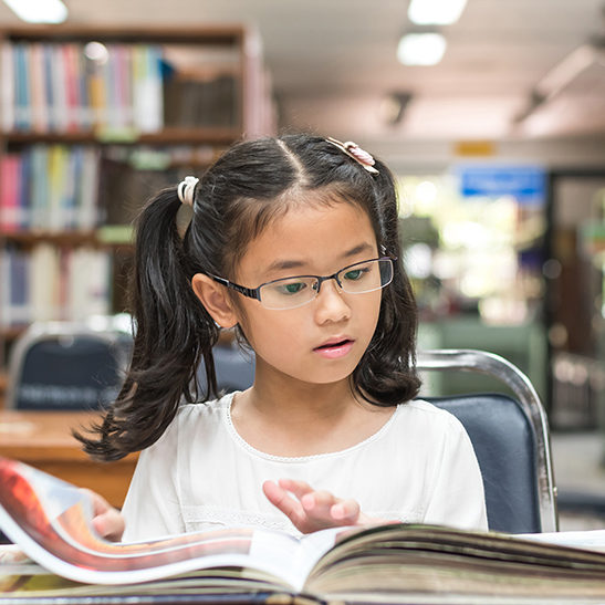 School education and literacy concept with Asian girl kid student learning and reading book in library or classroom